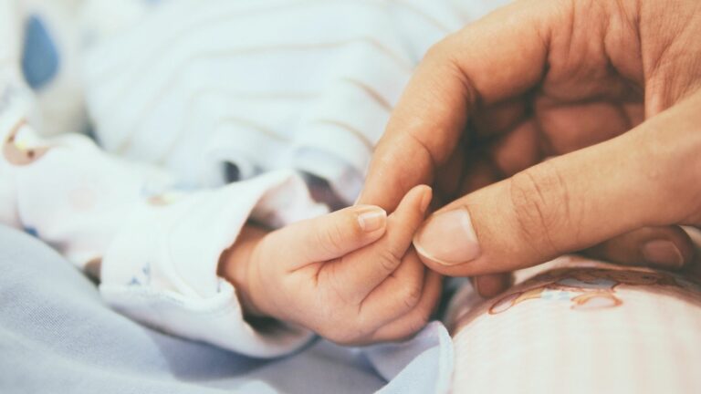 Adult hand holding baby hand