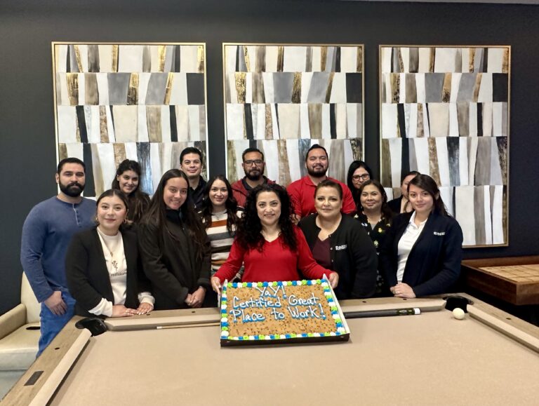 Rhodes staff holding a cookie to celebrate Great Place to Work Certification Day